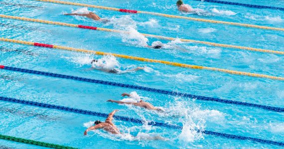 plusieurs personnes font la course dans une piscine d'intérieur