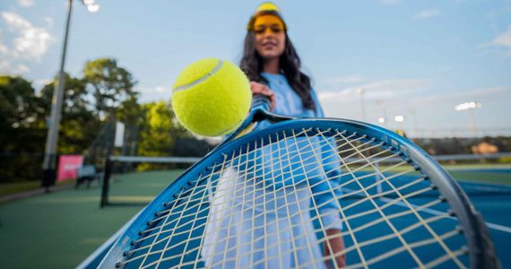 un femme fait rebondir une balle sur raquette de tennis