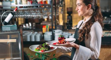 Waiter serving in motion on duty in restaurant. The waiter carries dishes